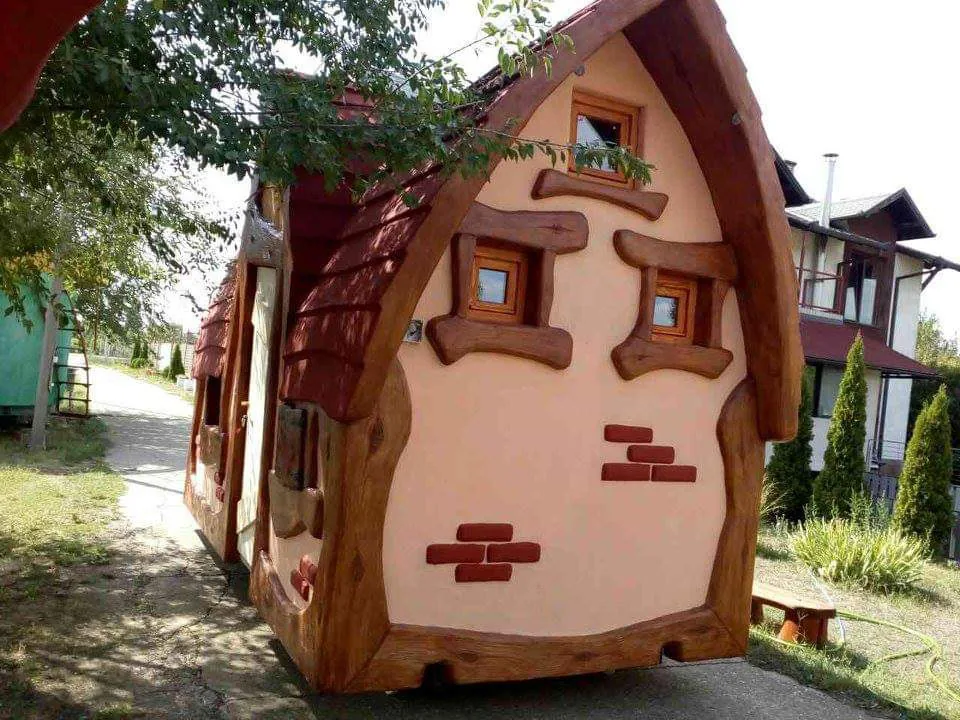 A crooked hand-sculpted fairy tale cottage with a curved red roof