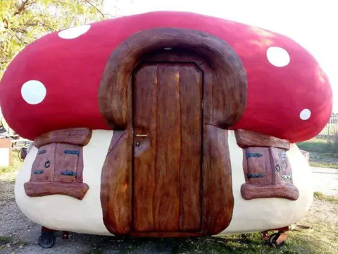 Red and white spotted mushroom house with a wooden door