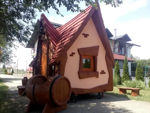 Hansel and Gretel style hut with a red roof and wooden barrels